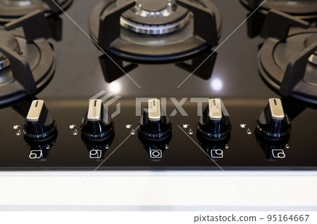 Modern kitchen and black glass ceramic built-in gas oven button detail 95164667