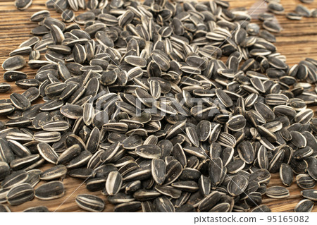 Sunflower Seeds, Striped Raw Seeds on Wood Background Texture Closeup Sunflower Seeds, Striped Raw Seeds on Wood Background Texture Closeup 95165082