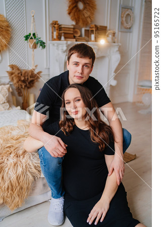 pregnant woman and man in black clothes. a couple hugging. 95165722