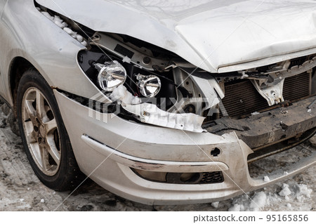Close-up detail view of broken wrecked front car part after road collision accident due icy snowy slippery road on winter city street. Crash vehicle part outdoors. Auto body insurance repair concept Close-up detail view of broken wrecked front car part after road collision accident due icy snowy slippery road on winter city street. Crash vehicle part outdoors. Auto body insurance repair concept 95165856