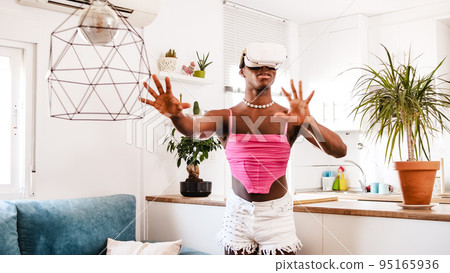 Non binary gamer person exploring virtual reality in living room at home Non binary gamer person exploring virtual reality in living room at home 95165936