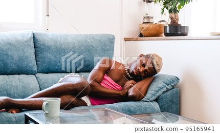 Sad and frustrated transgender person lies on the sofa 95165941