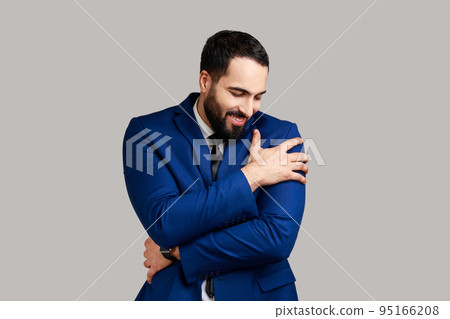 I am egoist, love myself. Portrait of selfish narcissistic bearded man embracing himself and smiling with dreamy satisfied expression. Indoor studio shot isolated on gray background. I am egoist, love myself. Portrait of selfish narcissistic bearded man embracing himself and smiling with dreamy satisfied expression. Indoor studio shot isolated on gray background. 95166208