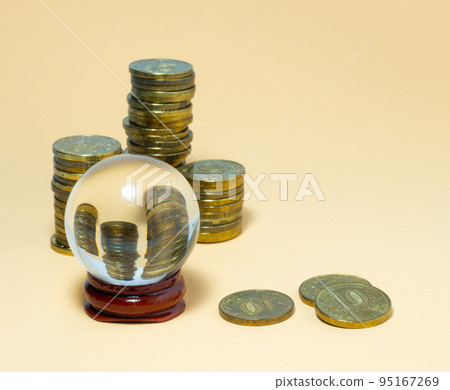 Pyramids of coins are reflected in a glass ball. 95167269