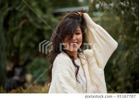 Portrait of pretty asian kazakh brunette woman with charming smile walking along outdoors Portrait of pretty asian kazakh brunette woman with charming smile walking along outdoors 95167707