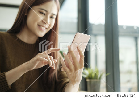 Young woman studying or working online using laptop and mobile phone. 95168424