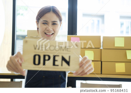 Female online business owner holding welcome, open sign. Female online business owner holding welcome, open sign. 95168431