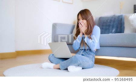 Young asian woman in good spirits working on laptop at home Young asian woman in good spirits working on laptop at home 95168495