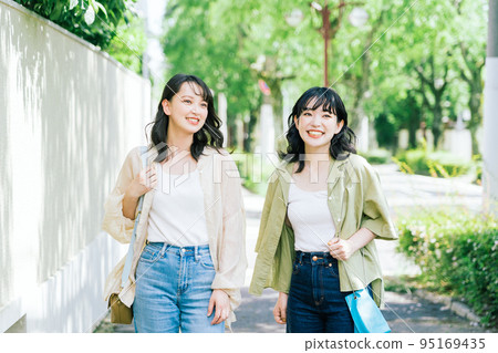 Female friends walking while chatting 95169435