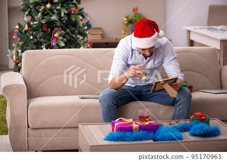 Young man celebrating Christmas at home alone 95170963