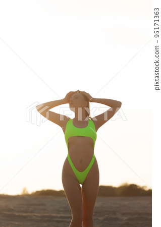 Fit alluring female tourist standing on seashore with hand on waist Fit alluring female tourist standing on seashore with hand on waist 95171363