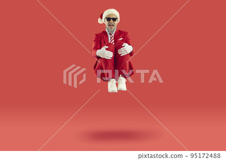 Old cheerful grey-haired man wearing Santa style is sitting levitating in air on red background. 95172488