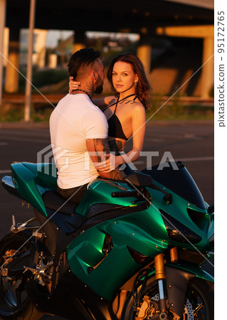 Couple hugging near motorbike at sunset Couple hugging near motorbike at sunset 95172765