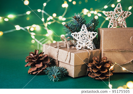 Christmas sustainable gift boxes with natural decor and shining garland on green background. Christmas zero waste Christmas sustainable gift boxes with natural decor and shining garland on green background. Christmas zero waste 95175505