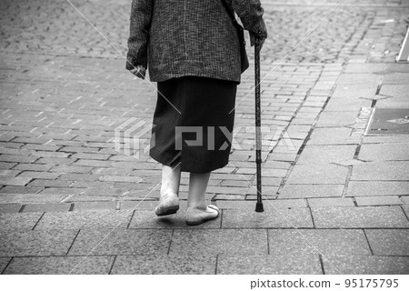 closeup of legs of old woman walking in the street with stick in black and white closeup of legs of old woman walking in the street with stick in black and white 95175795