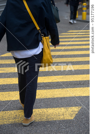 Closeup of legs of woman crossing the street on yellow zebra Closeup of legs of woman crossing the street on yellow zebra 95177196
