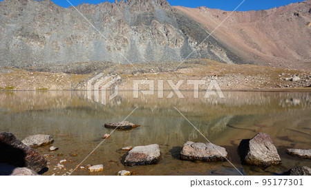 Transparent mountain lake surrounded by high cliff 95177301