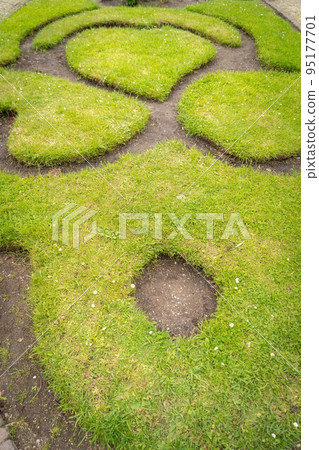 Figure made of green lawn grass in the park, free space. Green grass covered topiary, landscape design. Grass figure, topiary figure. 95177701