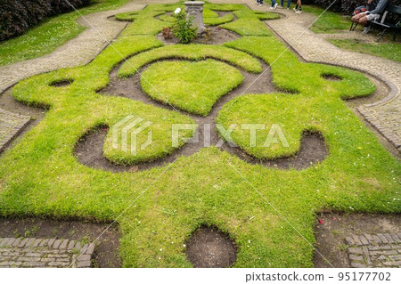 Figure made of green lawn grass in the park, free space. Green grass covered topiary, landscape design. Grass figure, topiary figure. 95177702