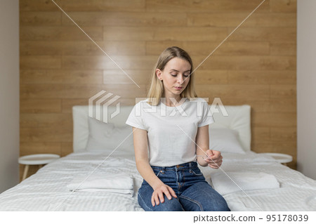 Happy young beautiful woman at home sitting on the couch, holding a quick pregnancy test in her hands, learned about pregnancy, rejoices, surprise 95178039