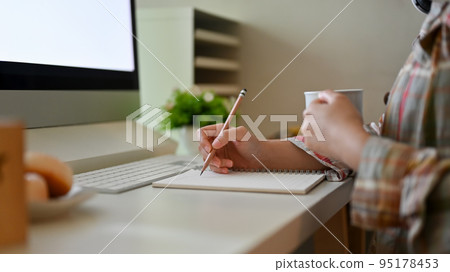A hipster female in a flannel shirt writing something in her notebook and sipping coffee A hipster female in a flannel shirt writing something in her notebook and sipping coffee 95178453