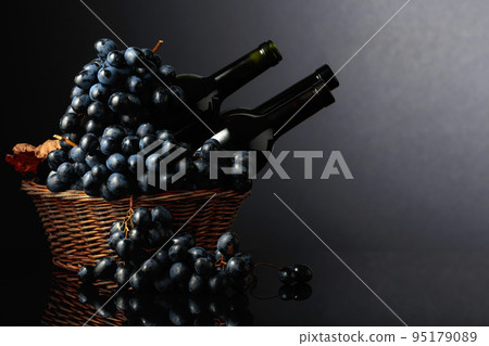 Red wine and blue grapes on a black reflective background. Red wine and blue grapes on a black reflective background. 95179089