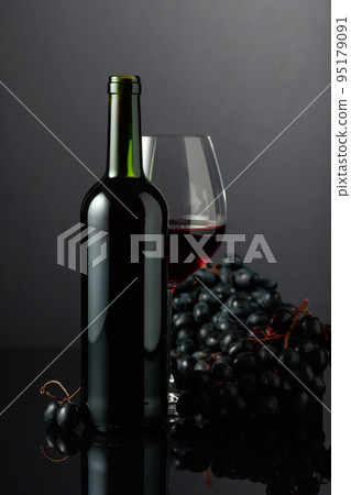 Red wine and blue grapes on a black background. Red wine and blue grapes on a black background. 95179091