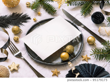 Black and golden Christmas Table setting with a card, ornaments and fir tree branches. Mockup Black and golden Christmas Table setting with a card, ornaments and fir tree branches. Mockup 95179173