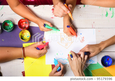 Hands hold colorful markers and draw, top view 95179396