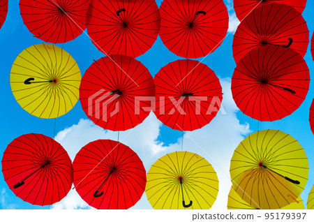 Umbrella background. Multicolored parasols hanging in sky bottom- up. Street decoration 95179397