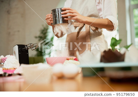 Sifting flour for dough. Cropped image of culinary specialist writes video blog on baking. Female vlogger or shooting blog filming reportage Sifting flour for dough. Cropped image of culinary specialist writes video blog on baking. Female vlogger or shooting blog filming reportage 95179650