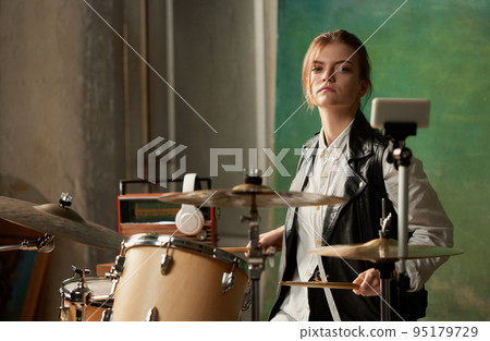 Emotional young girl, rock musician recording music video blog home lesson, playing drums or making broadcast internet tutorial while sitting at record label 95179729