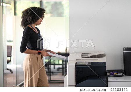 Woman in balck shirt and beige pants in the office looking determined Woman in balck shirt and beige pants in the office looking determined 95183151