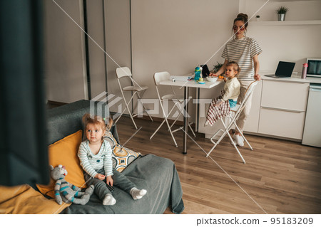 Female parent and her kids watching TV at breakfast Female parent and her kids watching TV at breakfast 95183209
