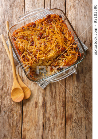 Sweet Yerushalmi kugel made of noodles, raisins and burnt sugar close-up in a glass bowl. Vertical top view Sweet Yerushalmi kugel made of noodles, raisins and burnt sugar close-up in a glass bowl. Vertical top view 95183590