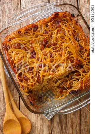 Caramelized Noodle and Pepper Yerushalmi Kugel with raisins close-up in a glass bowl. Vertical top view 95183592
