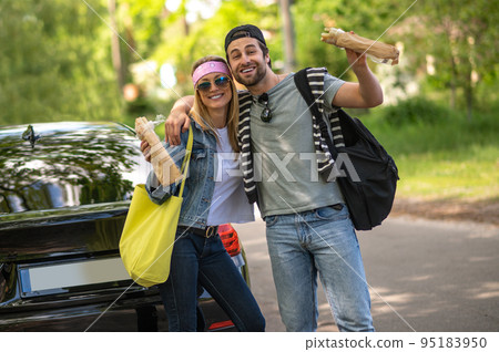Cute young couple looking excited and joyful standing near the car Cute young couple looking excited and joyful standing near the car 95183950