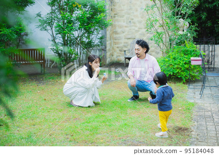 A family blowing soap bubbles in the garden 95184048