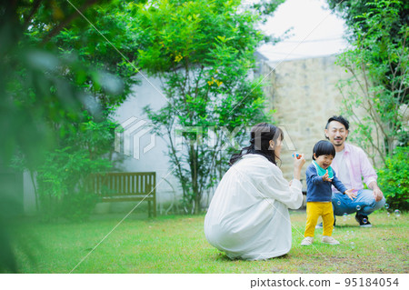 A family blowing soap bubbles in the garden 95184054