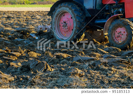 Tractor plows the autumn field after harvesting 95185313