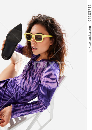 Portrait of stylish young girl in purple dress posing over white background. Talking on shoe Portrait of stylish young girl in purple dress posing over white background. Talking on shoe 95185711