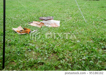 Preparing a bonfire at a grassy campsite Preparing a bonfire at a grassy campsite 95186182