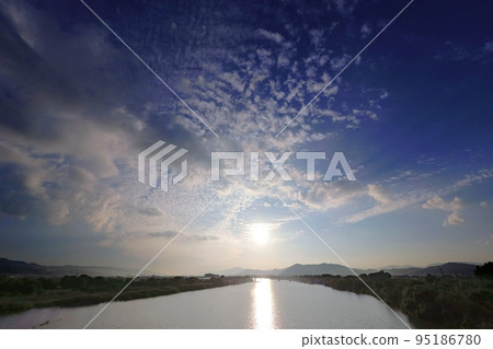 A refreshing autumn morning sky with various clouds and a river surface reflecting the sun, super wide angle, sky mainly, 221001am 95186780