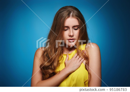 young woman in yellow t-shirt on blue background. young woman in yellow t-shirt on blue background. 95186783