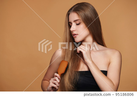woman combs her long natural hair with wooden brush woman combs her long natural hair with wooden brush 95186806