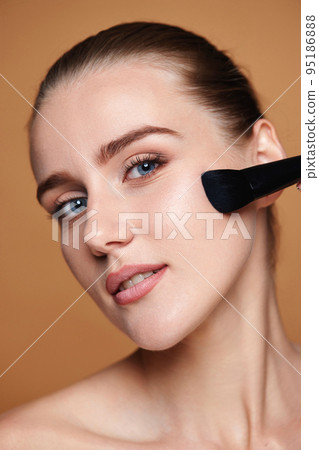 woman applying blush on cheeks with make-up brush woman applying blush on cheeks with make-up brush 95186888