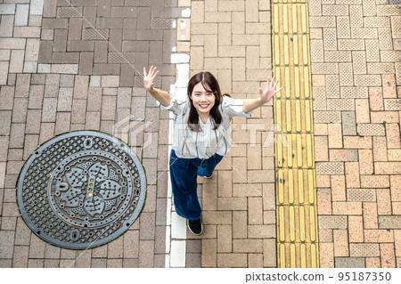 走在城市裡的年輕女子揮手鳥瞰 95187350