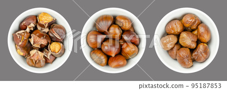 Unshelled, roasted and boiled chestnuts, marrons in white bowls over gray. Sweet chestnuts, Castanea sativa, eaten raw, candied, cooked, milled into flour, or roasted as warm snack, sold on streets. 95187853