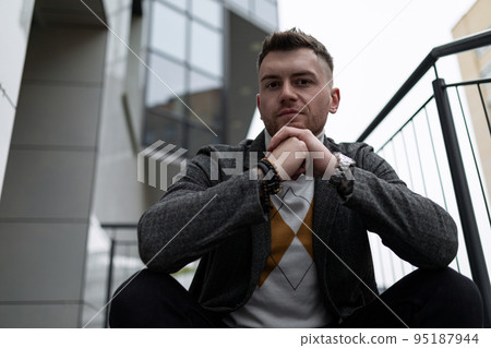 brutal portrait of a man sitting on the stairs with his hands folded in the lock brutal portrait of a man sitting on the stairs with his hands folded in the lock 95187944