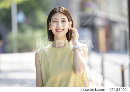 Portrait of a smiling young woman standing on a street corner Portrait of a smiling young woman standing on a street corner 95188401